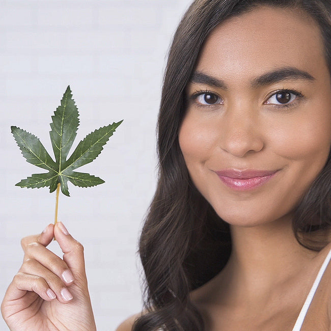 Smiling model holding a hemp leaf